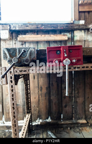 Vieux vices attachés à un workbench dans un hangar abandonné Banque D'Images