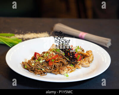 Nouilles de sarrasin Soba, oignon, carotte, poivron, bulgare, cuisses de poulet, hot chili peppers sauce Chili, l'oignon vert. Banque D'Images