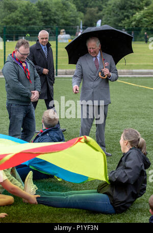 Le Prince de Galles, abris sous un parapluie activités pendant qu'il observe lors d'une visite au Centre communautaire de Gortin Owenkillew, dans le cadre de sa tournée de l'Irlande du Nord avec la duchesse de Cornouailles. Banque D'Images