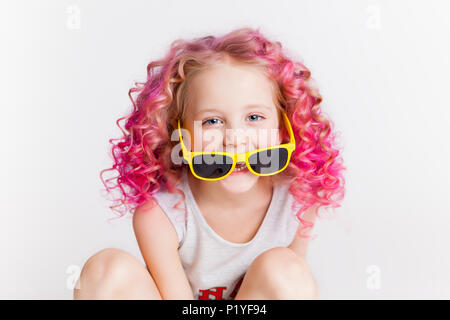 Les cheveux ondulés de couleur. Petite fille hipster moderne à la mode des vêtements, souriant. Studio. Isolated on white Banque D'Images