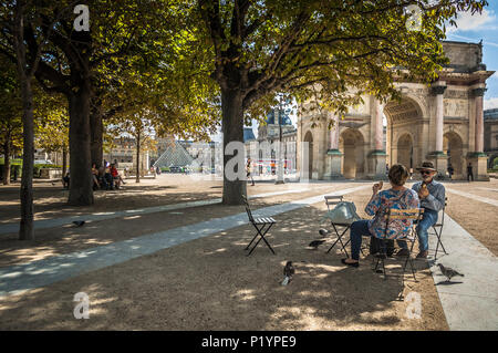 Couple français bénéficiant d'une collation dans un parc près du Louvre, entourée d'arbres. Banque D'Images