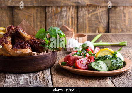 Pilons de poulet rôti Bol en céramique et en légumes frais sur la table de bois rustique, repas préféré Banque D'Images