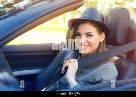 Jeune femme tirant sur l'intérieur de la ceinture de sécurité voiture noire. Les mesures de sauvetage Banque D'Images