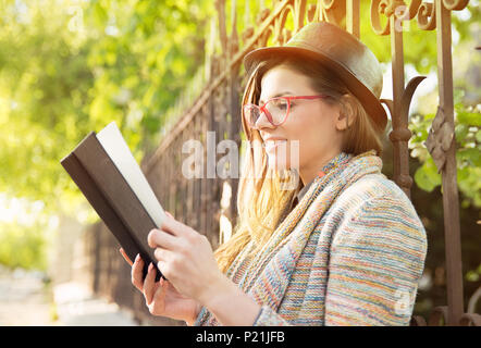 Jeune femme lisant un livre à l'extérieur Banque D'Images