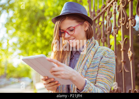 Happy young woman using tablet computer outdoors Banque D'Images