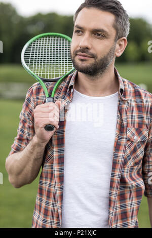 Beau barbu holding badminton racquet sur l'épaule et à l'écart Banque D'Images