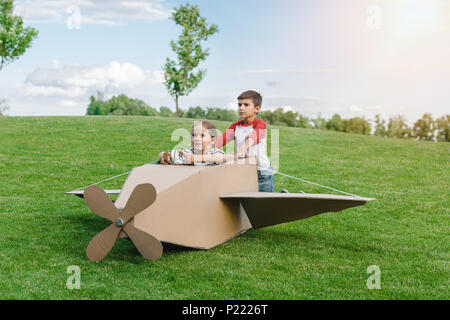 Adorables petits enfants jouant avec diy avion sur pré vert dans la région de park Banque D'Images