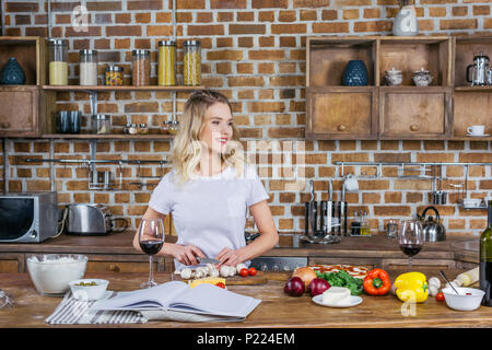 Smiling blonde woman cooking pizza et à l'écart dans la cuisine Banque D'Images