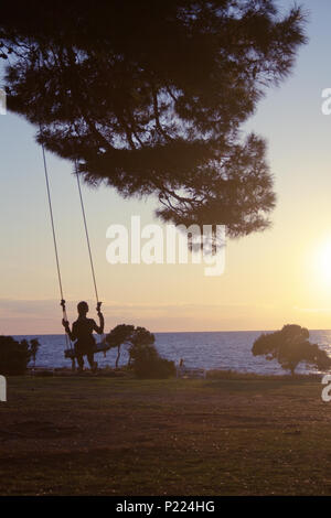 Jeune femme se balançant au coucher du soleil - tout simplement magnifique Banque D'Images