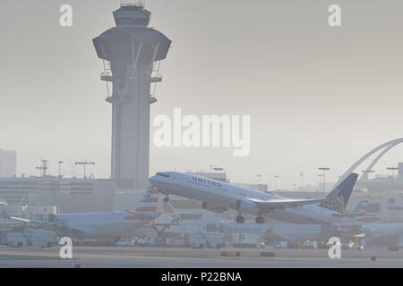 United Airlines Boeing 737-900 Jet passagers décollant de l'Aéroport International de Los Angeles, LAX, après le lever du soleil, la tour de contrôle en arrière-plan. Banque D'Images