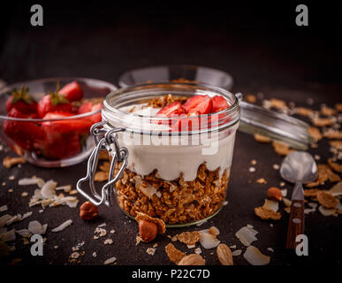 Granola maison posée avec le yogourt et fraises en pot de verre ouvert Banque D'Images