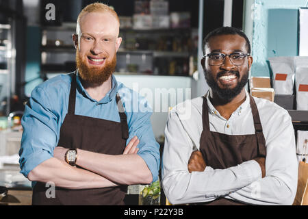 Portrait de deux jeunes propriétaires multiethnique de coffee shop à tabliers article writing in coffee shop Banque D'Images