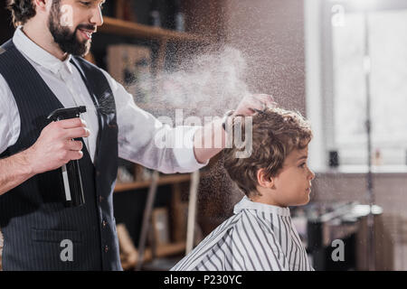 Barbu souriant peignage des cheveux coiffure et la pulvérisation de gamin Banque D'Images