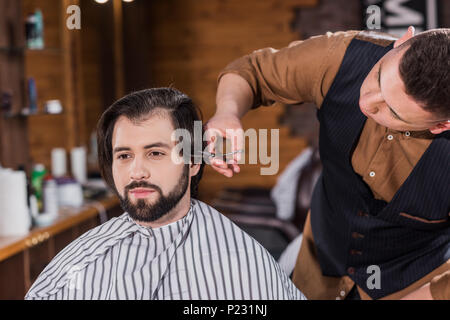 Beau jeune homme se coupe de coiffure professionnel au salon de coiffure Banque D'Images