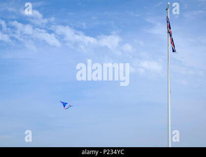 Union Jack drapeau sur mât contre un ciel bleu avec un cerf-volant en vol à proximité Banque D'Images