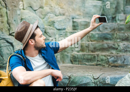 Jeune homme attrayant en tenant assis sur selfies escalier de pierre Banque D'Images