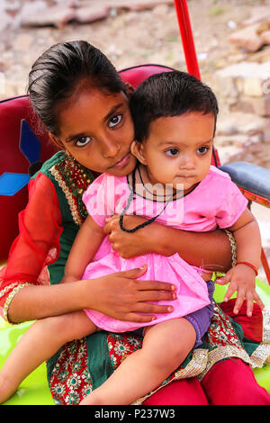 Fille avec une fille de bébé assis dans la rue, dans le quartier de Taj Ganj Agra, Uttar Pradesh, Inde. L'Agra est l'une des villes les plus peuplés dans l'Uttar P Banque D'Images