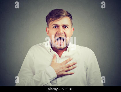 Jeune homme extrêmement choqué à la main sur la poitrine et à la bouche avec de l'appareil photo à l'ouverture. Banque D'Images