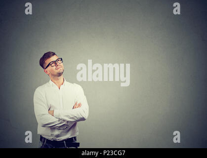 Bel homme en chemise blanche et verres à la rêverie et à rêver de carrière. Banque D'Images