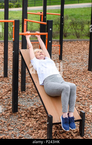 Femme âgée sportive faisant abs sur terrain de sport Banque D'Images