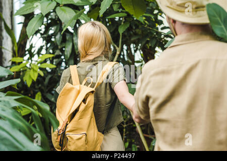 Vue arrière du jeune couple dans safari suits holding hands par in jungle Banque D'Images