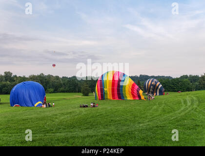 Biella, Italie, 10 juin 2018 -Trois montgolfières étant fixés et dégonflé après le vol, et un ballon dans le ciel en juin, fête du printemps Banque D'Images