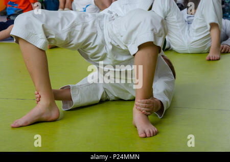 Un garçon dans le kimono de karaté pratiquant sur le sol dans la salle de sport Banque D'Images