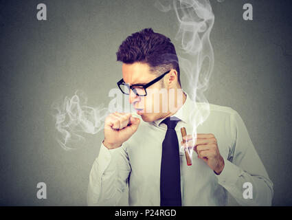 Homme fumant un cigare et la toux isolé sur fond gris Banque D'Images