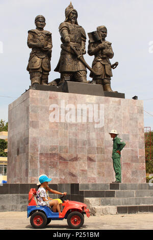 Phan Thiet , Viêt Nam - Janvier 2014 : Enfants conduire dans la petite voiture électrique en face de policier et statue au cours de nouvel an à Phan Thiet , Vietnam Banque D'Images