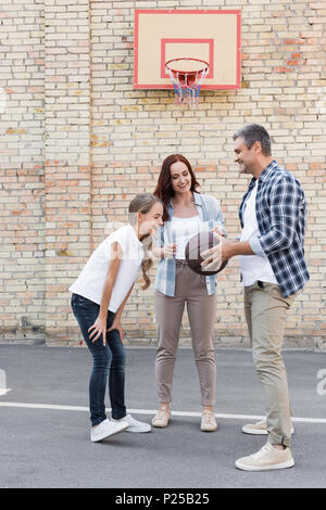 Famille heureuse jouant au basket-ball ensemble sur des jeux pour enfants Banque D'Images