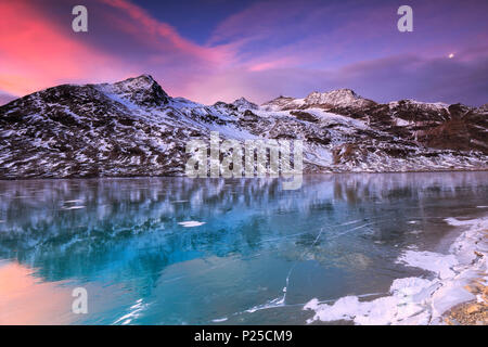 Superbe lever de soleil sur le lac gelé Bianco(Lac Blanc), Col de la Bernina, Engadine, Grisons, Suisse. Banque D'Images