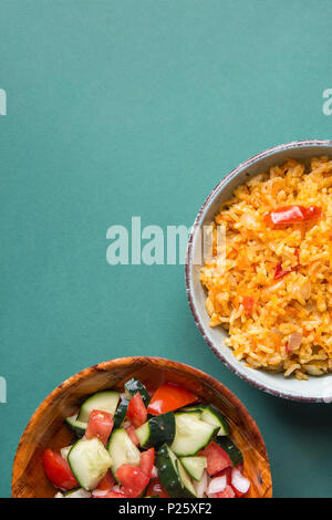 National mexicain traditionnel riz pilaf compote de tomates avec Hot Chili Peppers l'ail dans un bol Turquoise. Oignon concombre Salade Salsa dans un plat en bois Banque D'Images