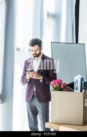 Le feu young businessman using smartphone près de Fort de trucs personnels at office Banque D'Images