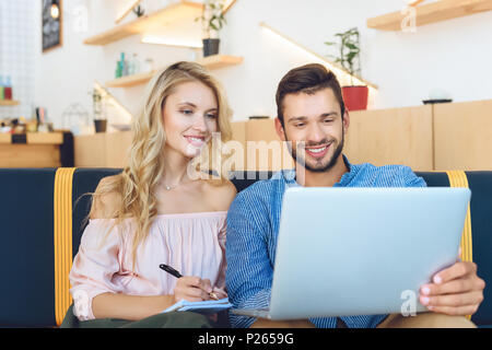 Smiling young couple et prendre des notes en cafe Banque D'Images