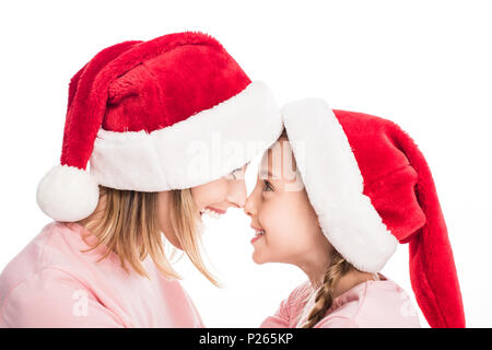 Smiling mother and daughter wearing santa hats de toucher le nez, isolated on white Banque D'Images