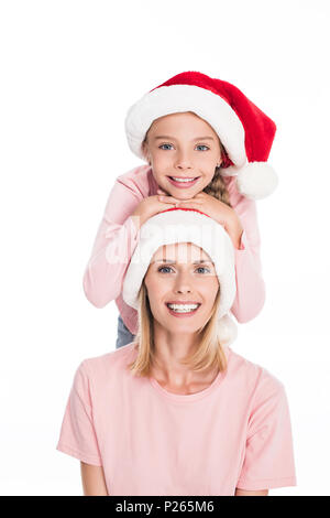 Fille souriante wearing santa hat avec sa tête sur le dessus de la tête de sa mère Banque D'Images