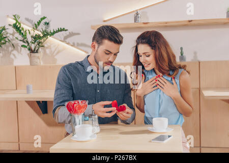 Portrait de l'homme faire de proposition à heureux petite amie sur date dans cafe Banque D'Images