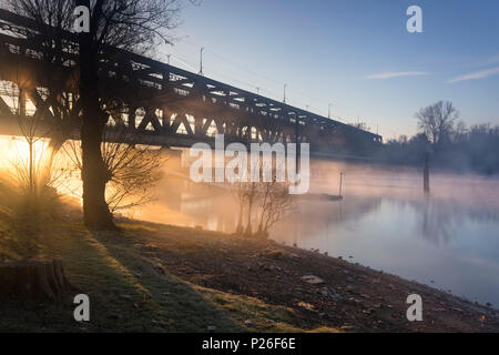 Les rayons de la lumière passer à travers le Ponte di Ferro dans un matin d'automne brumeux sur les rives de la rivière Tessin. Sesto Calende, Lac Majeur, Province de Varèse, Lombardie, Italie. Banque D'Images