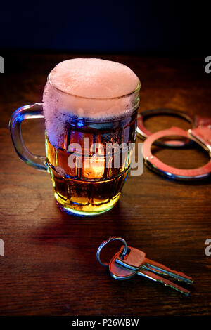 Chope de bière mousseuse avec des menottes et clés symbolisant l'alcool au volant l'arrestation Banque D'Images