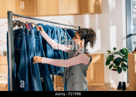 Belle jeune femme le choix de jeans dans une boutique de vêtements Banque D'Images