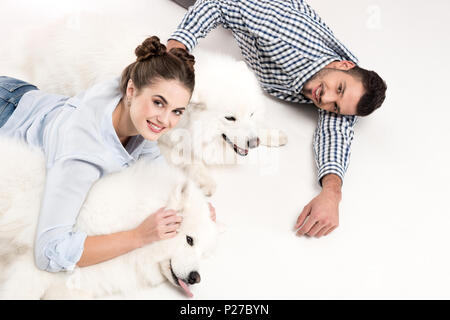 Vue de dessus de couple lying with dogs on white Banque D'Images