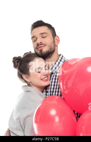 Couple hugging and holding ballons en forme de cœur isolé sur blanc, concept de Jour de Valentines Banque D'Images