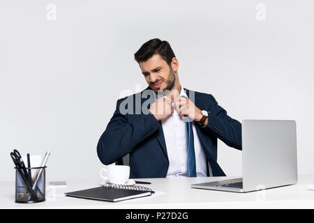 Young businessman adjusting necktie surchargés en étant assis sur le lieu de travail Banque D'Images