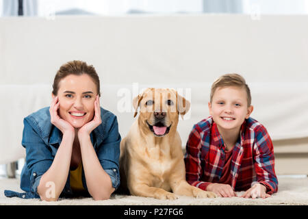 Happy mother and son lying on floor avec leur chien et looking at camera Banque D'Images
