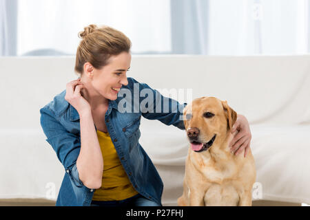 Femme de flatter son labrador chien à la maison Banque D'Images