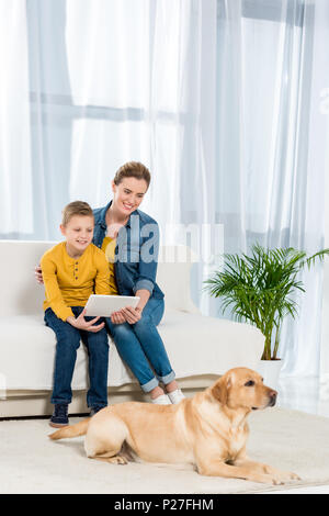 La mère et le fils à l'aide de tablet avec dog lying on floor on foreground Banque D'Images
