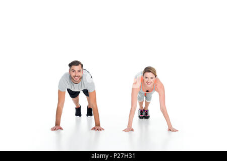 Cheerful athletic couple doing push ups ensemble isolated on white Banque D'Images