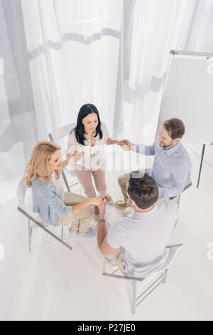 Vue supérieure de l'âge moyen des gens assis et tenir la main pendant la thérapie de groupe Banque D'Images
