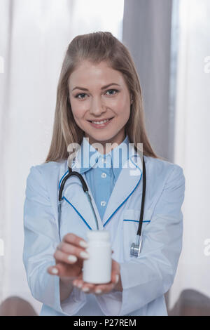 Smiling female doctor showing pills pot de plastique Banque D'Images