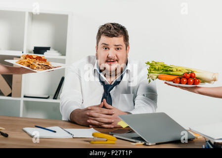 Homme d'embonpoint ou choisir des aliments vides à vert au travail Banque D'Images